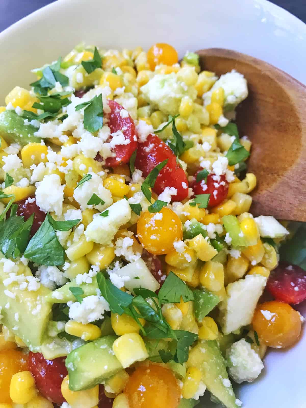 close up of serving spoon digging into the  bowl of salad