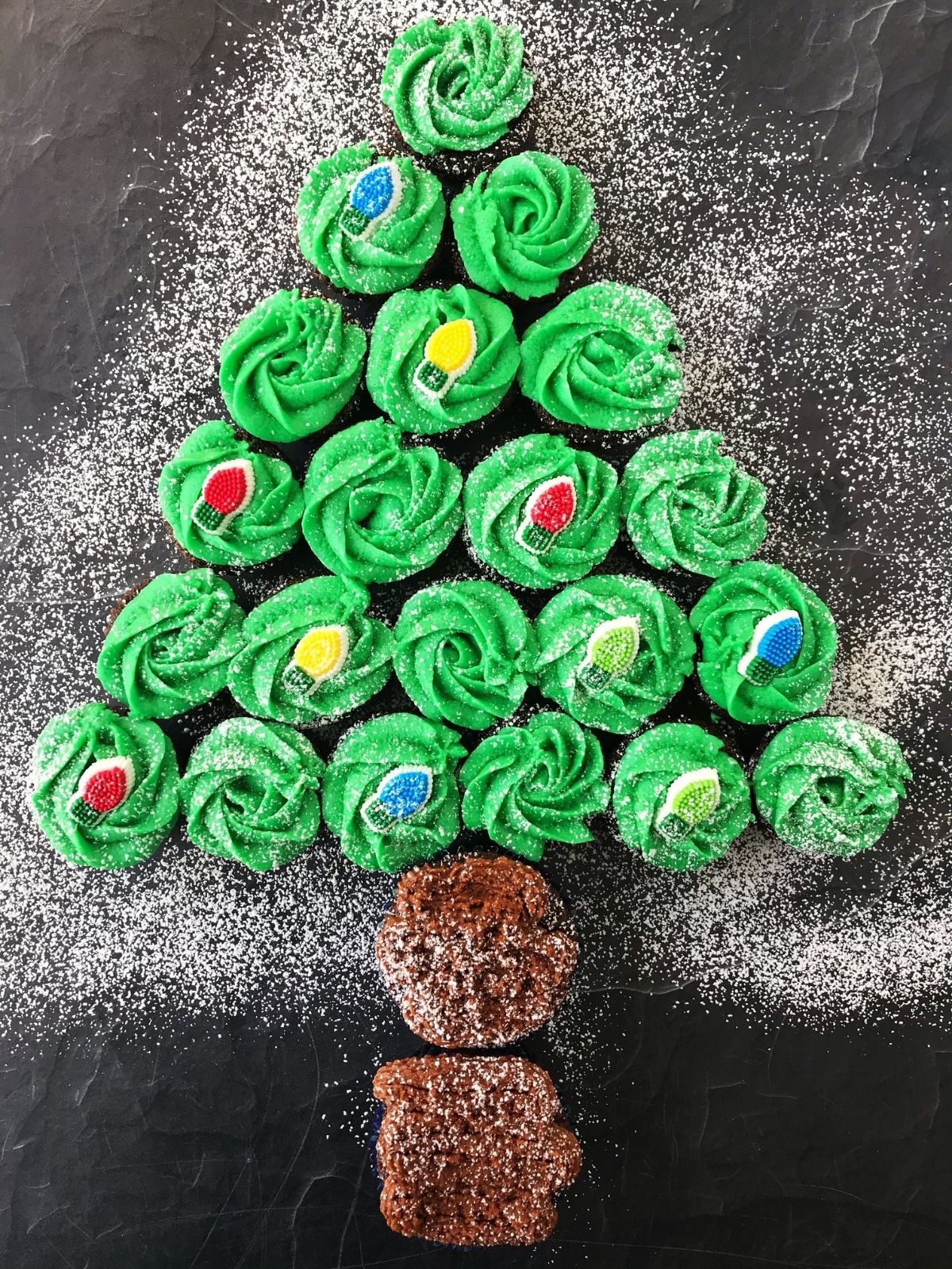 cupcakes arranged in Christmas tree from with a dusting of powdered sugar