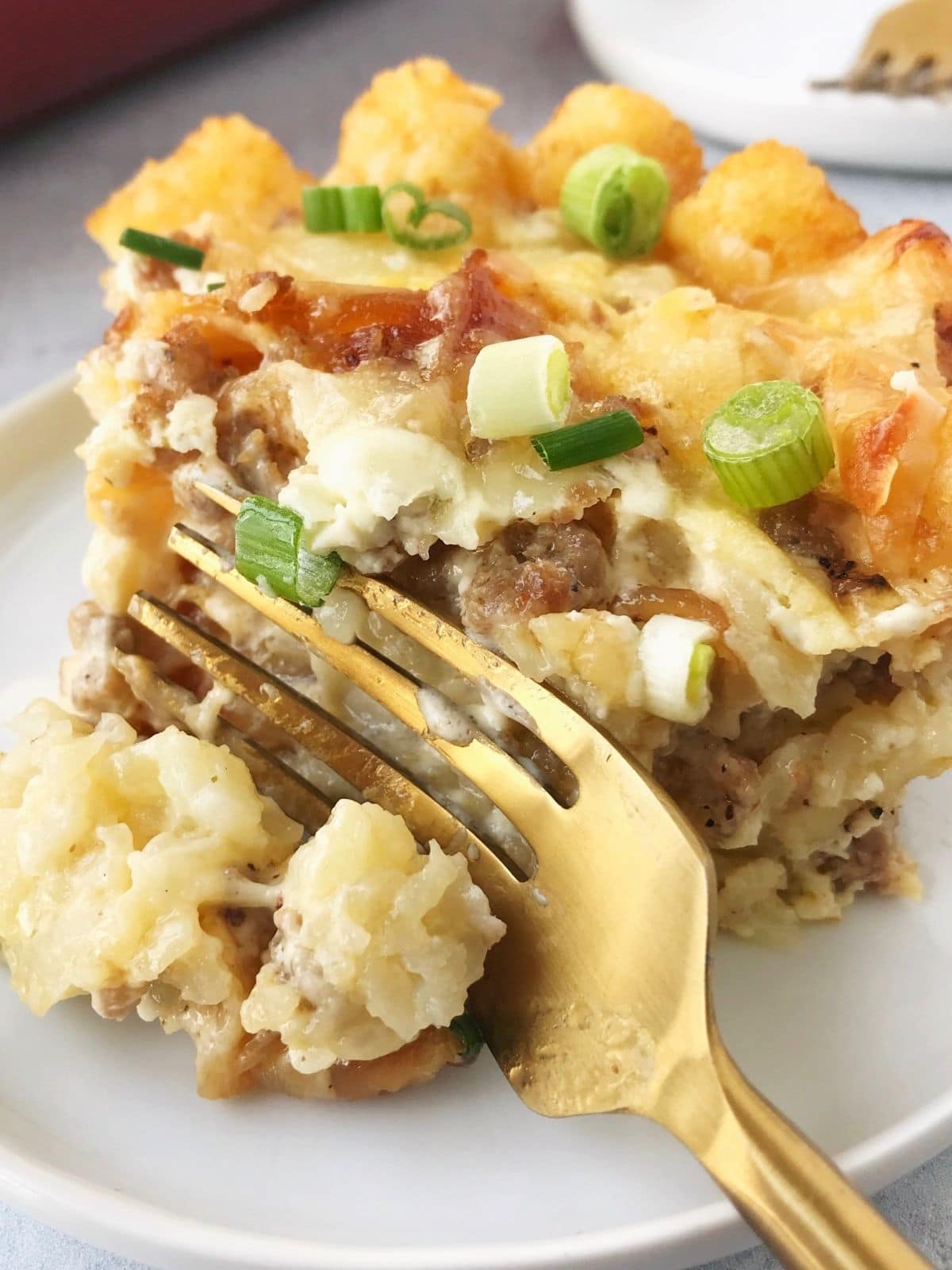 fork slicing a piece of casserole on a white plate