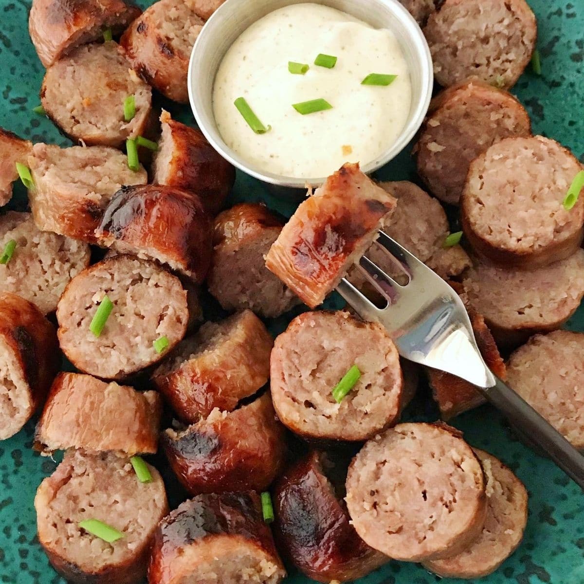 plate of sliced brats with sauce