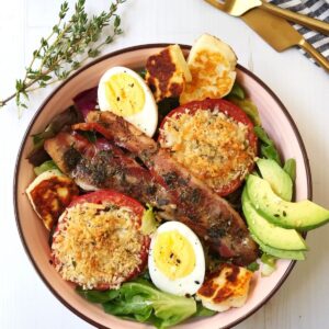 bowl filled with greens, eggs, bacon, roasted tomatoes