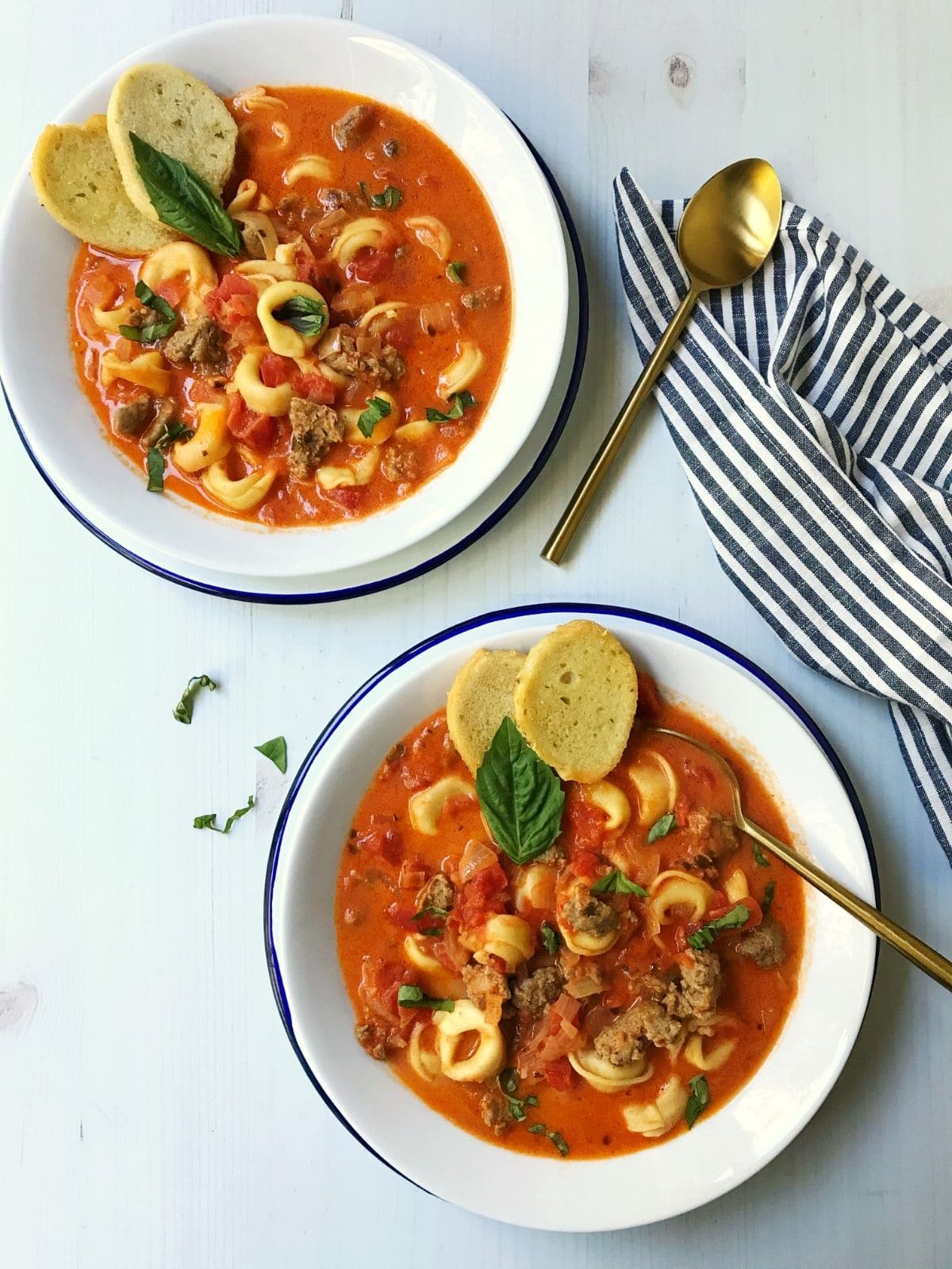 two bowls of soup with gold spoons