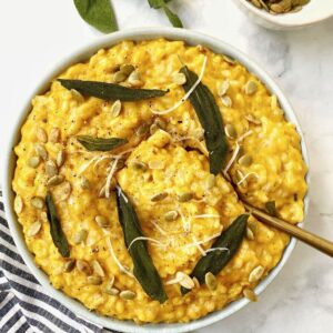 bowl of risotto with sage leaves and serving spoon