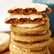 A stack of frosted cookies by a glass of milk.