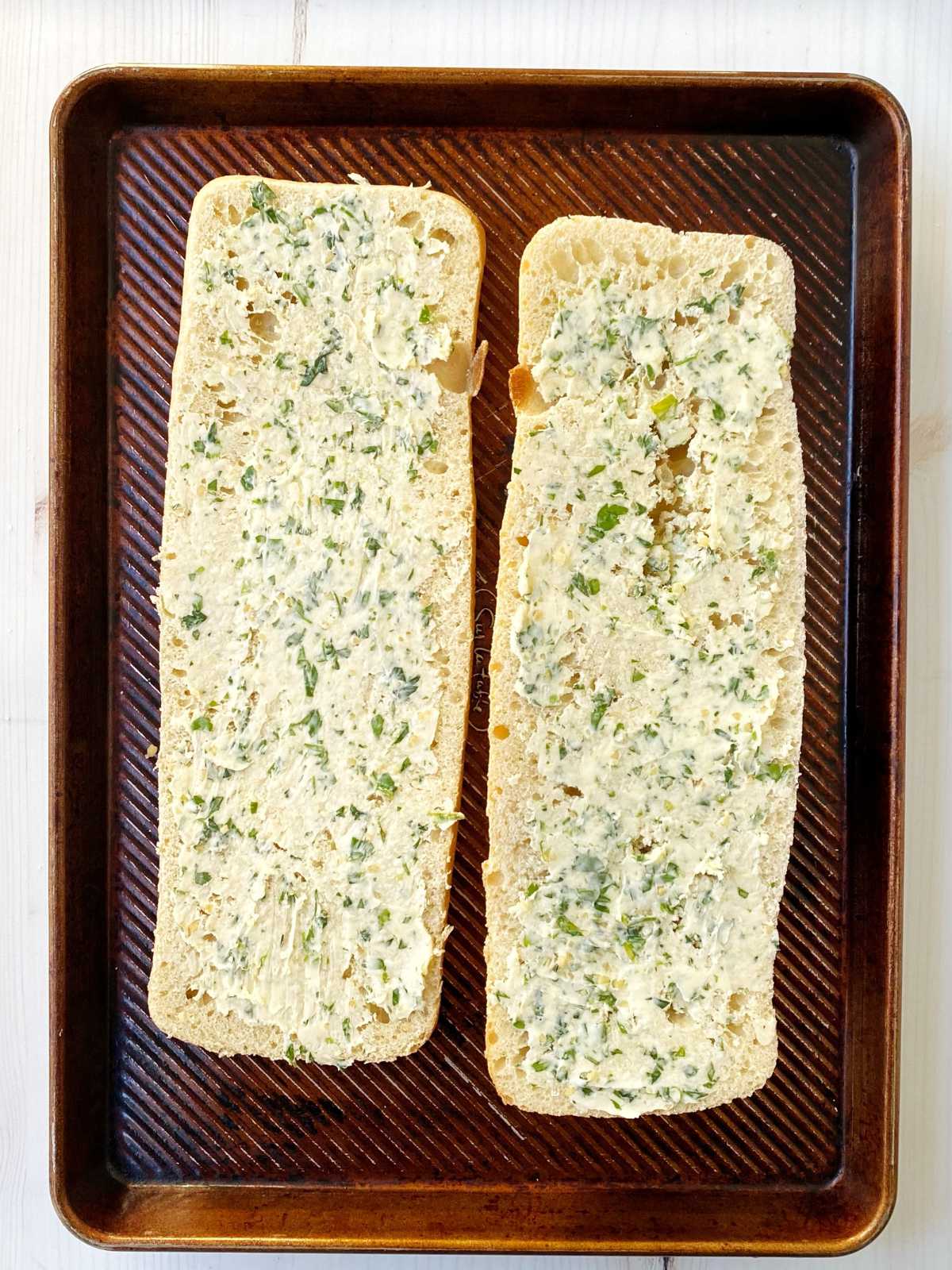 Bread sliced in half and spread with butter mixture.