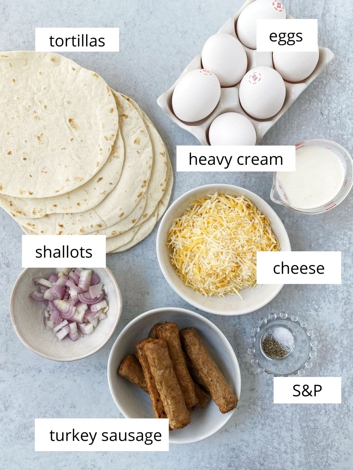 array of ingredients - eggs, sausage, cheese, tortillas, shallots, cream, salt and pepper