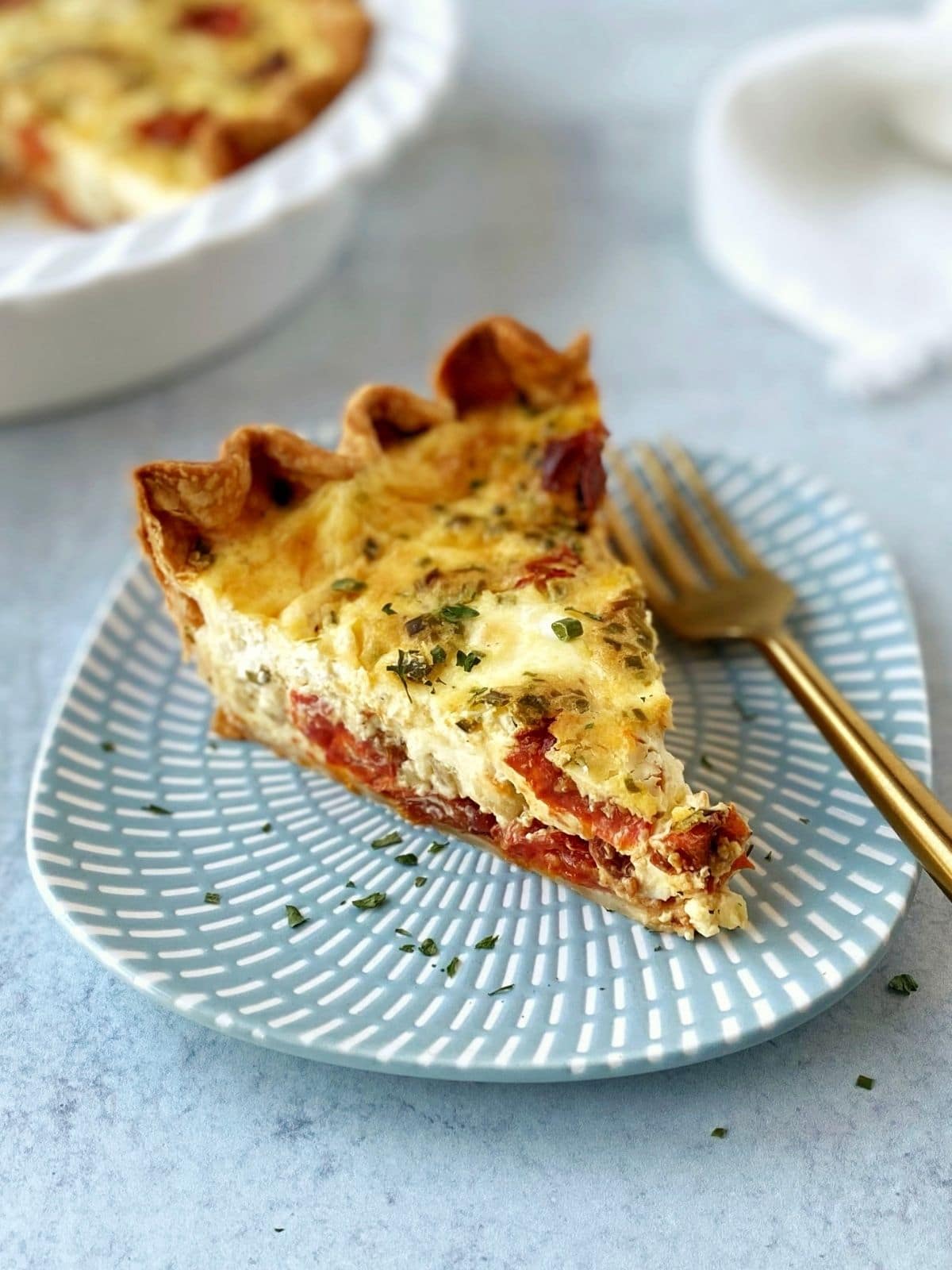 slice of baked quiche on a plate with a fork