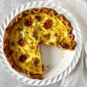 quiche in a pie plate with a slice gone