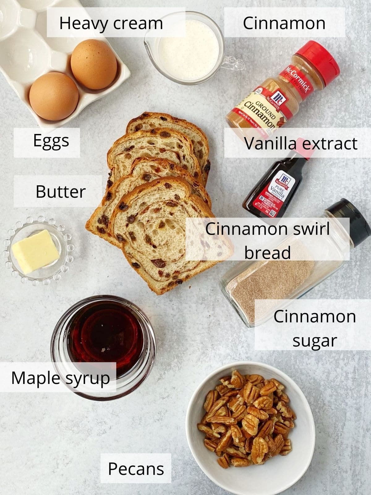 ingredients for french toast including bread, eggs, cream, butter, syrup, pecans, and seasonings