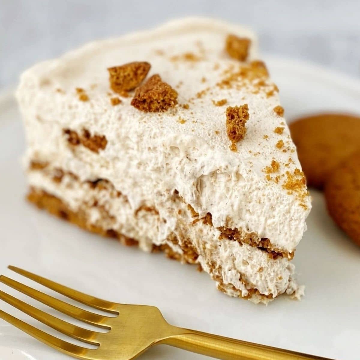 slice of cake on a plate with gingersnap cookies and a fork