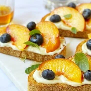 close up side view of peaches and ricotta on crostini.