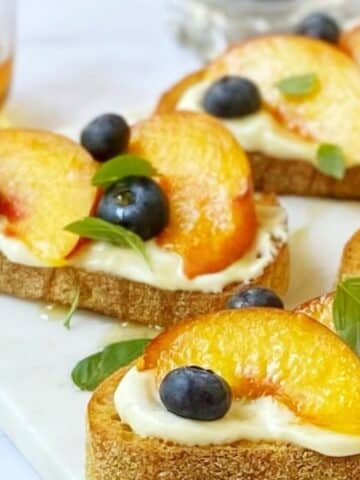 close up side view of peaches and ricotta on crostini.