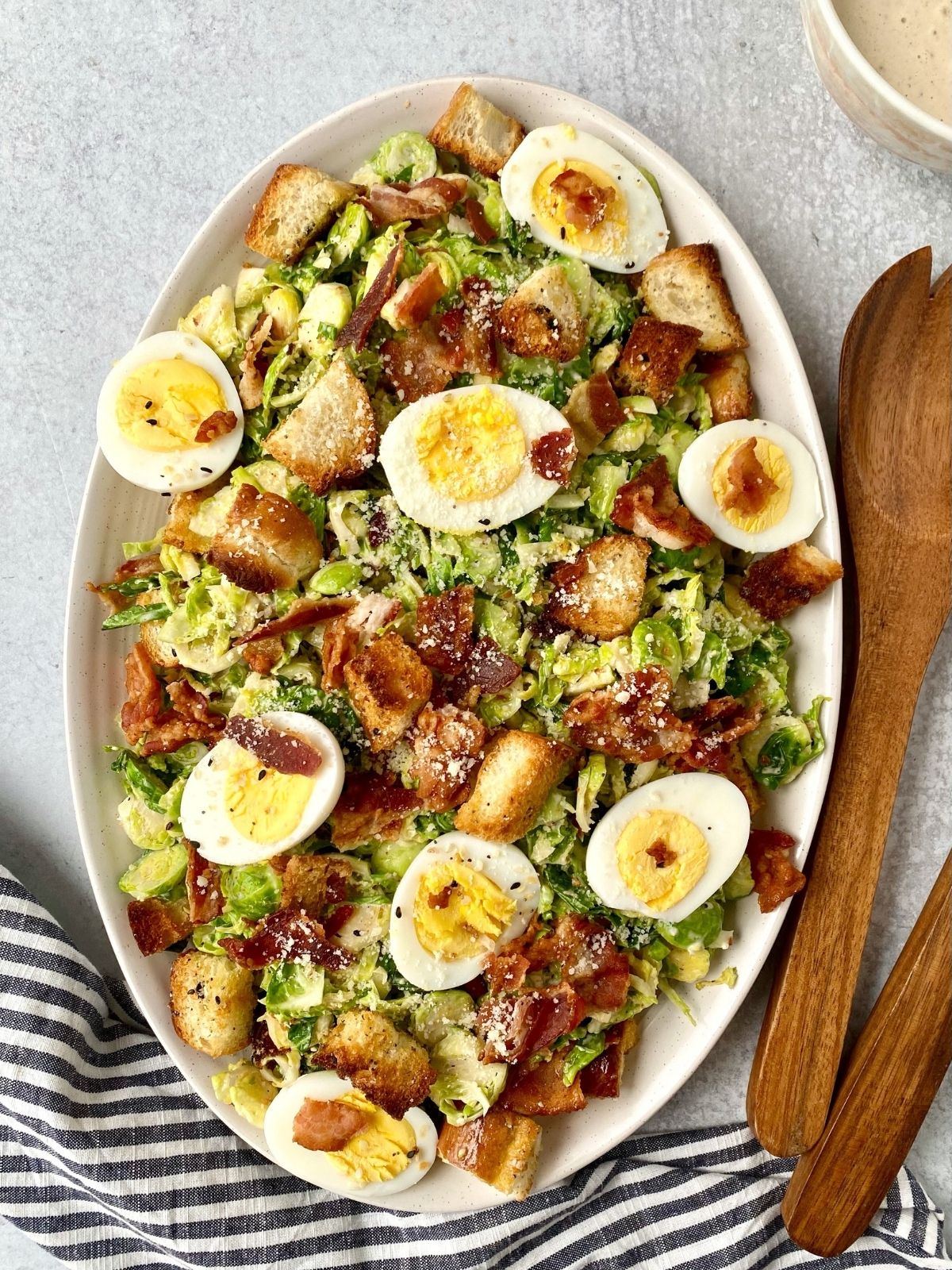 salad on platter with serving utensils on the side