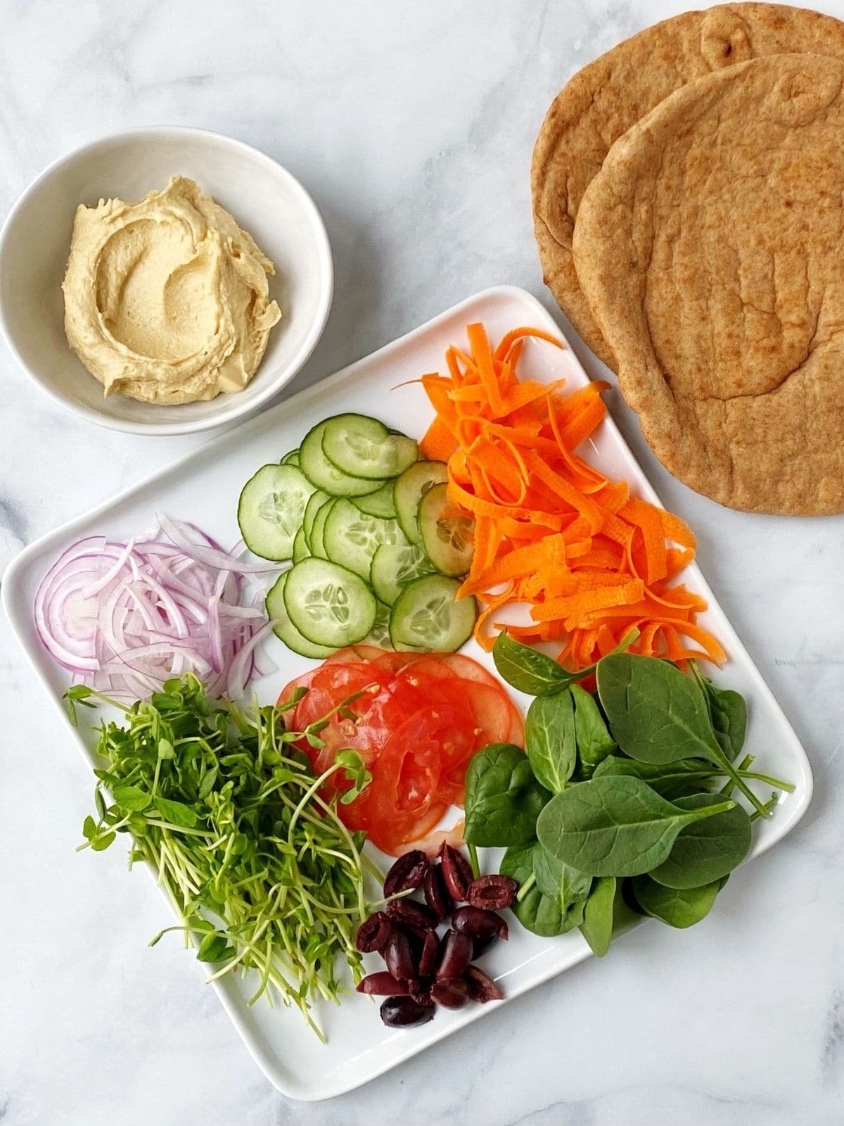 plate of sliced veggies, bowl of hummus, and pita bread