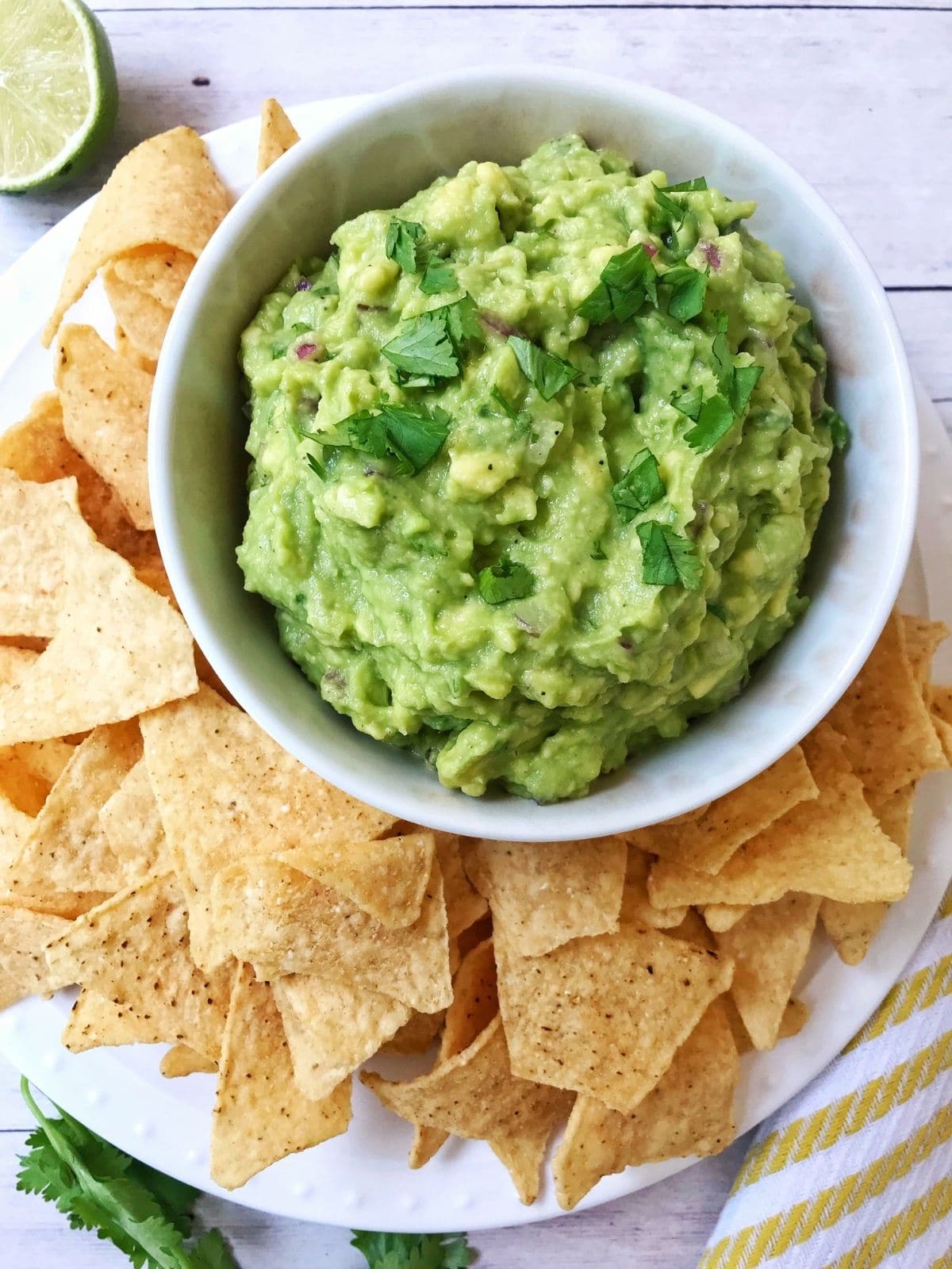 dish of guacamole on a platter with tortilla chips arranged on the side