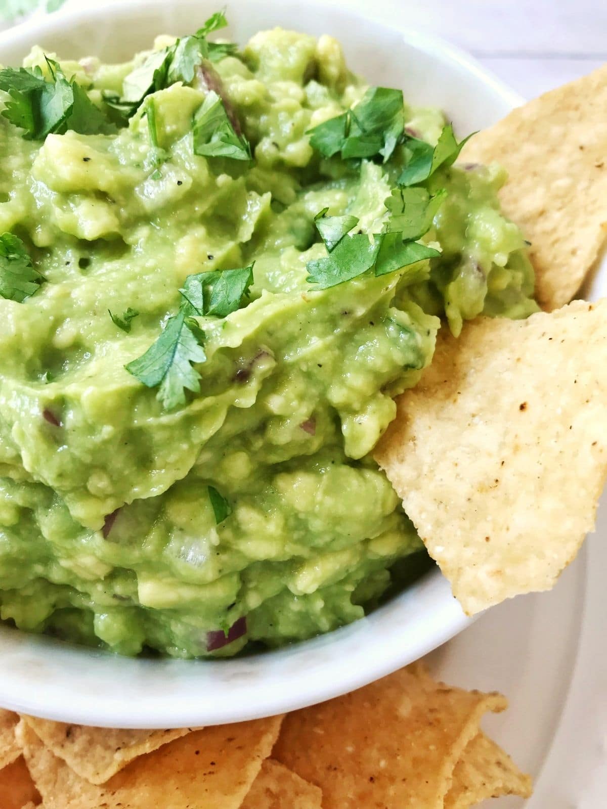 close up of avocado spread with chips digging in