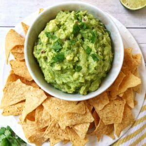 bowl of guacamole on serving platter with chips