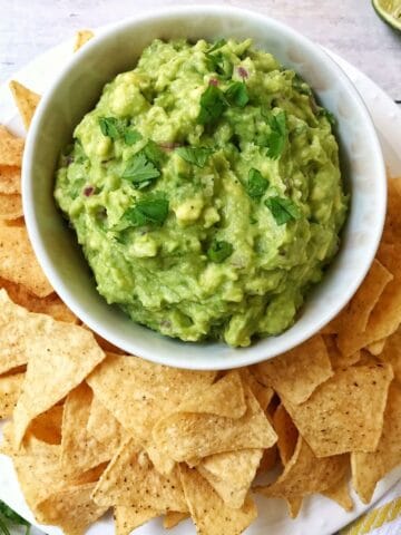 bowl of guacamole on serving platter with chips