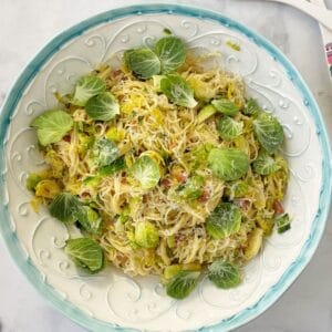 serving bowl of pasta garnished with brussels sprouts leaves