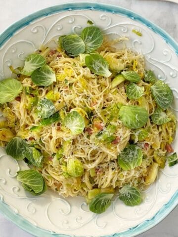 serving bowl of pasta garnished with brussels sprouts leaves