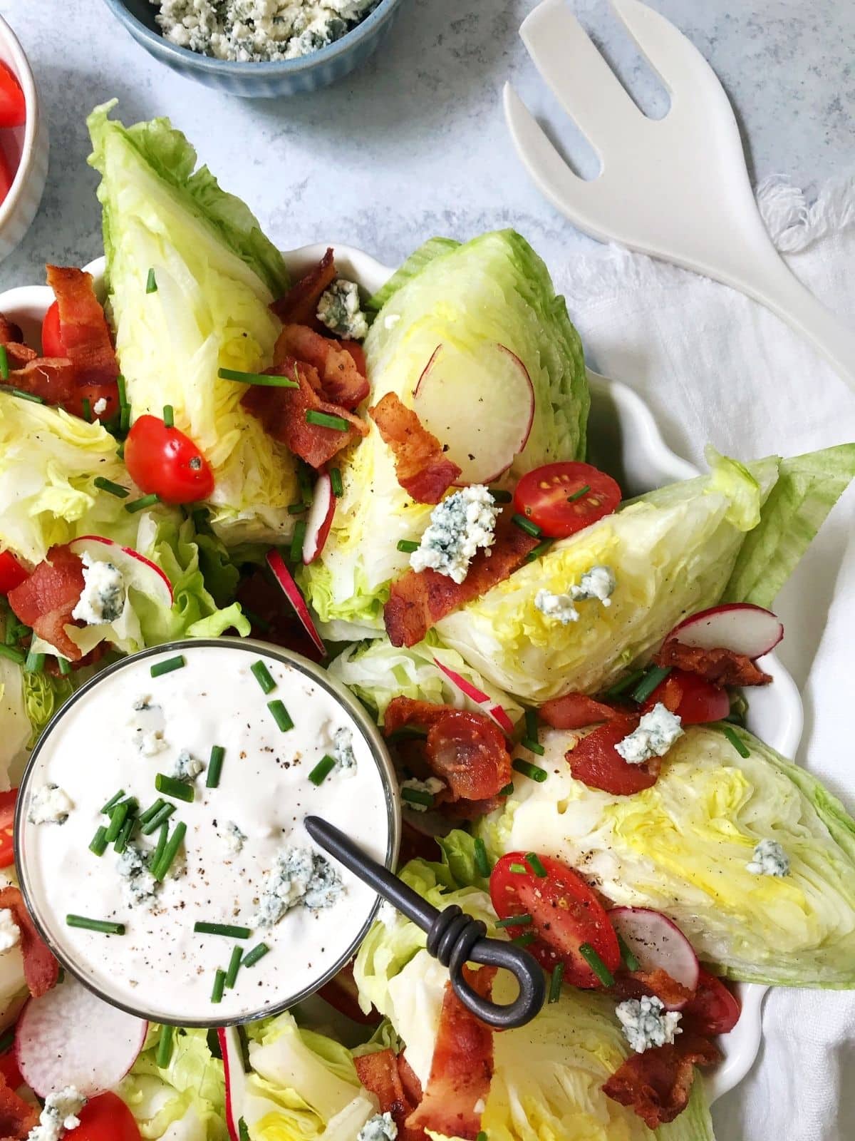 platter of lettuce wedges with serving utensil and extra blue cheese