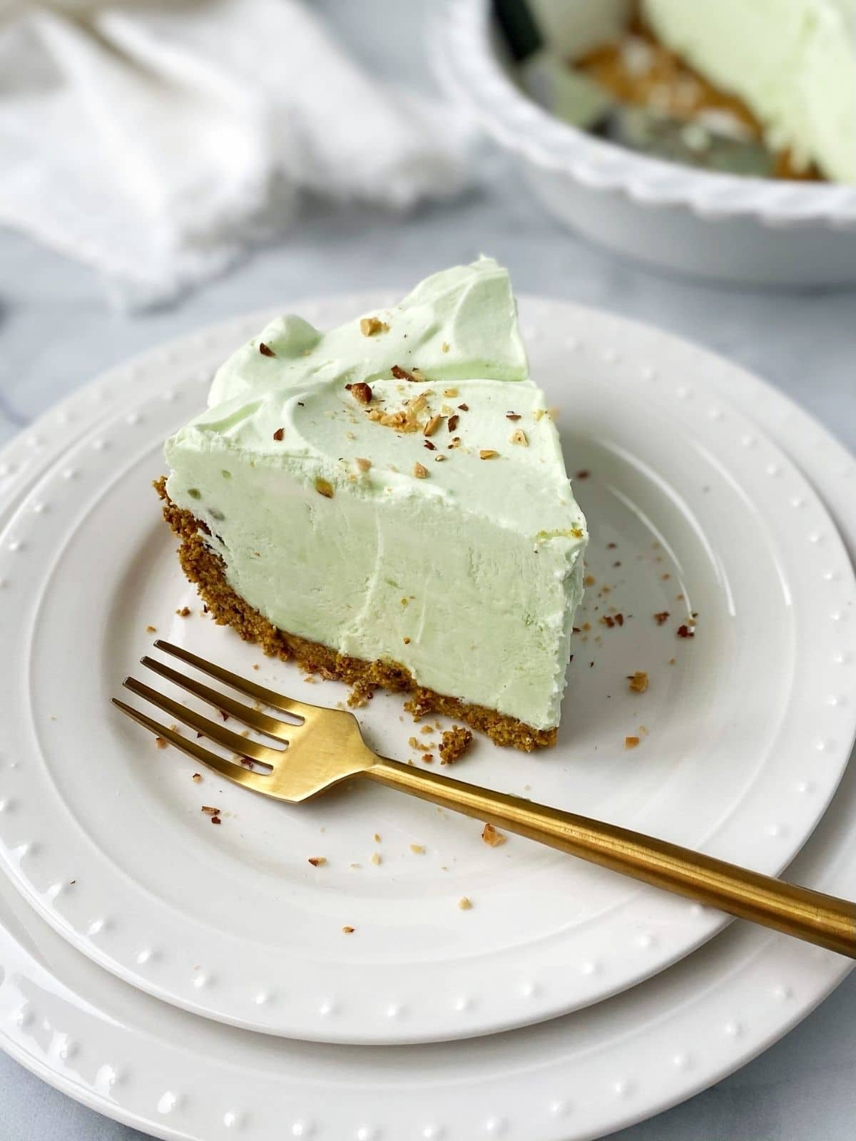 slice of pistachio pie on plate with a gold fork