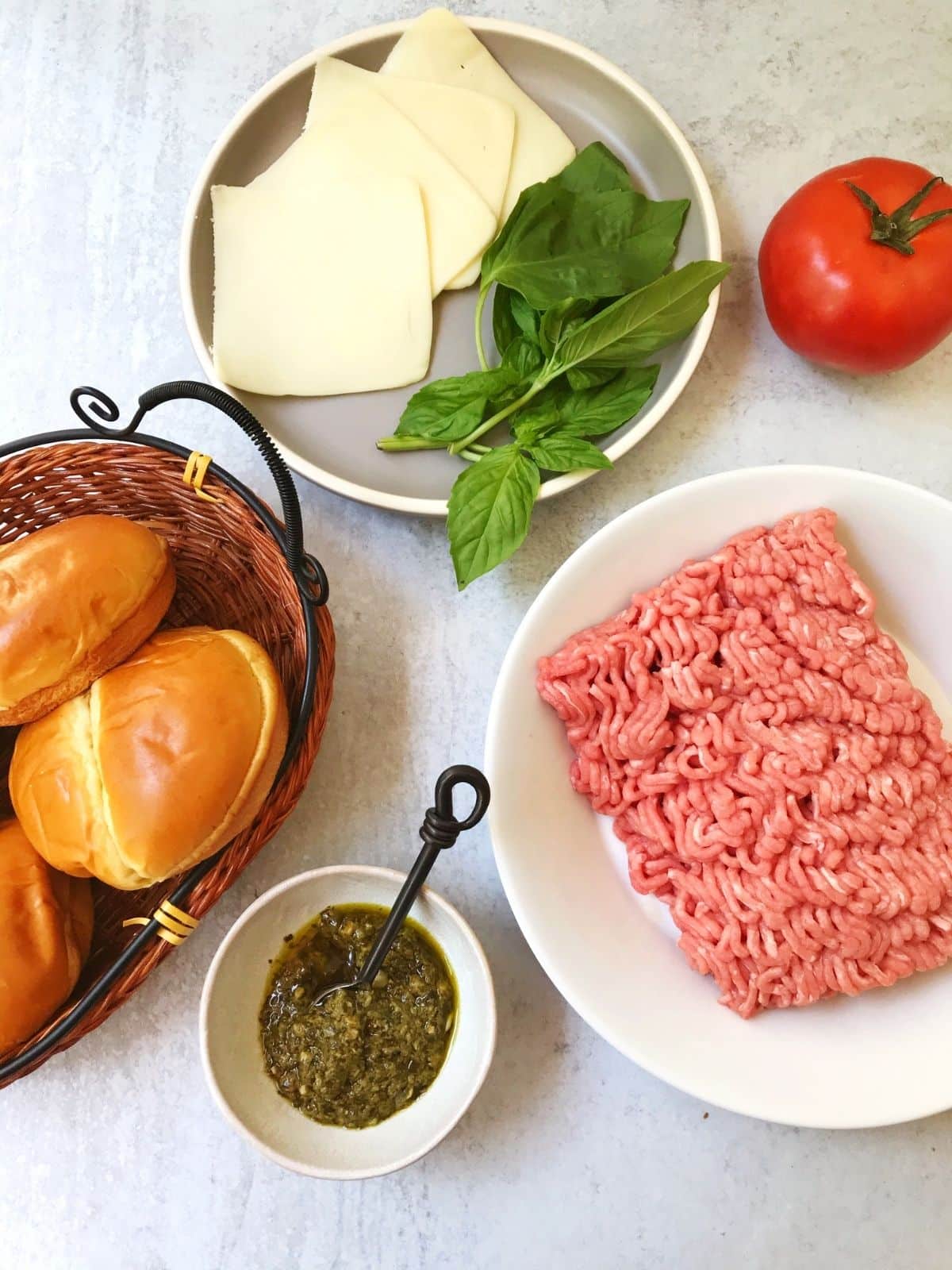 burger ingredients - ground turkey, rolls, pesto, tomatoes, cheese