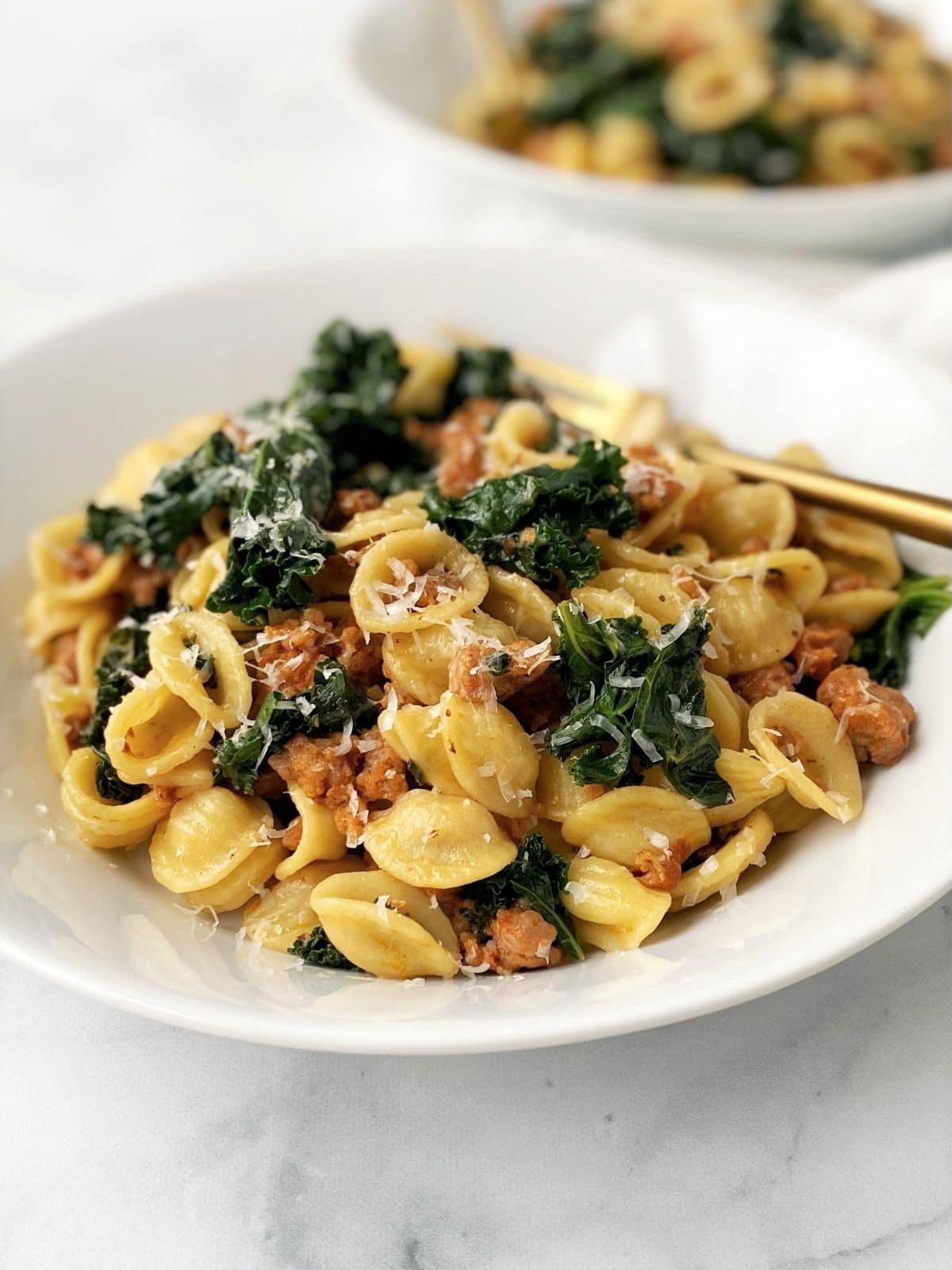 angled view of bowl of pasta with a gold fork