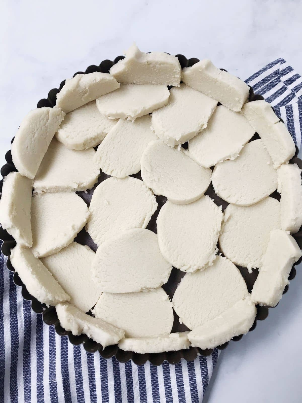 sliced dough arranged in tart pan to form crust