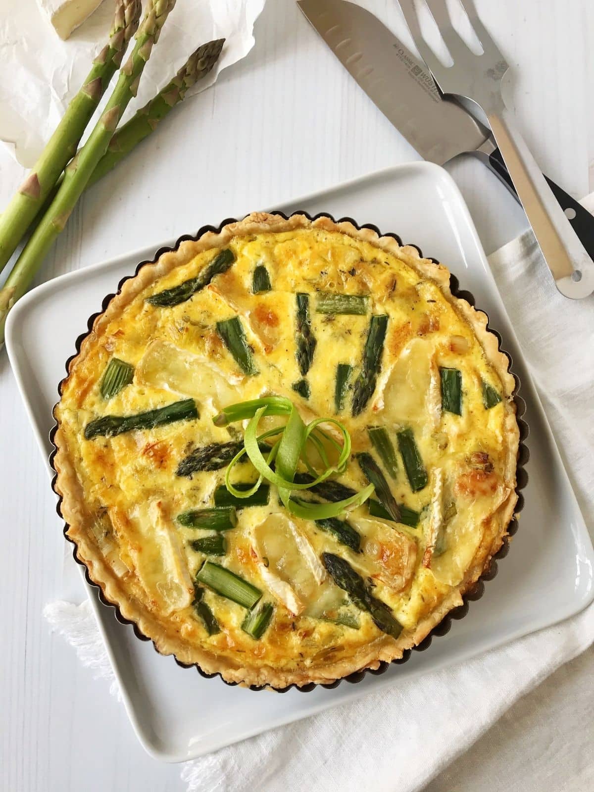 overhead shot of quiche with serving utensils on the side