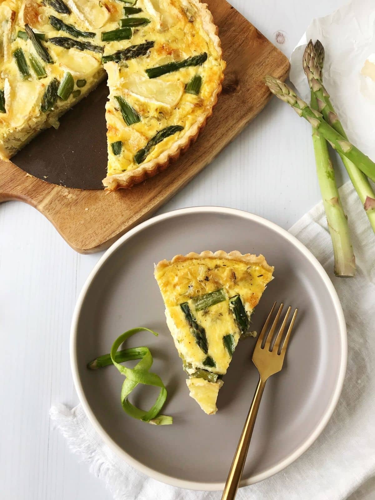 overhead shot of slice of quiche next to whole quiche on a cutting board
