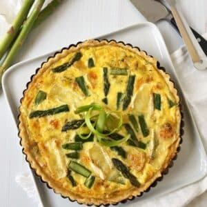 whole quiche with serving utensils on the side