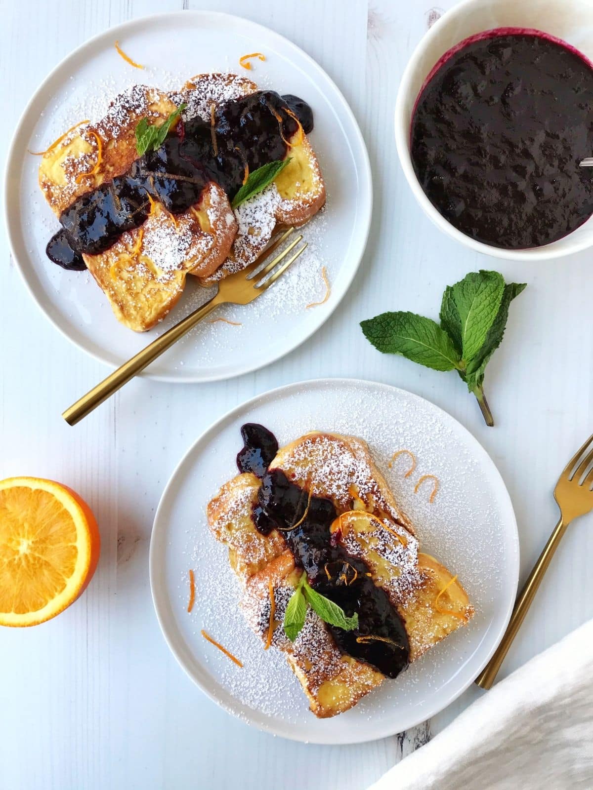 slices of french toast on white plates with syrup and mint leaves for garnish