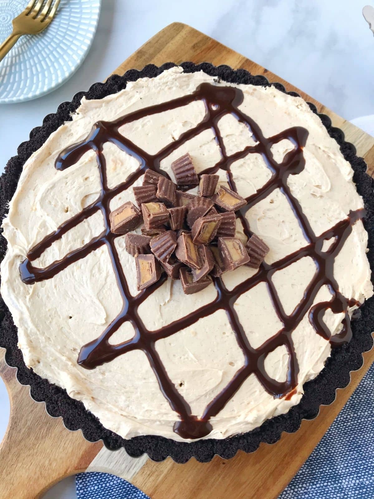 whole peanut butter tart garnished with chocolate sauce and peanut butter cups