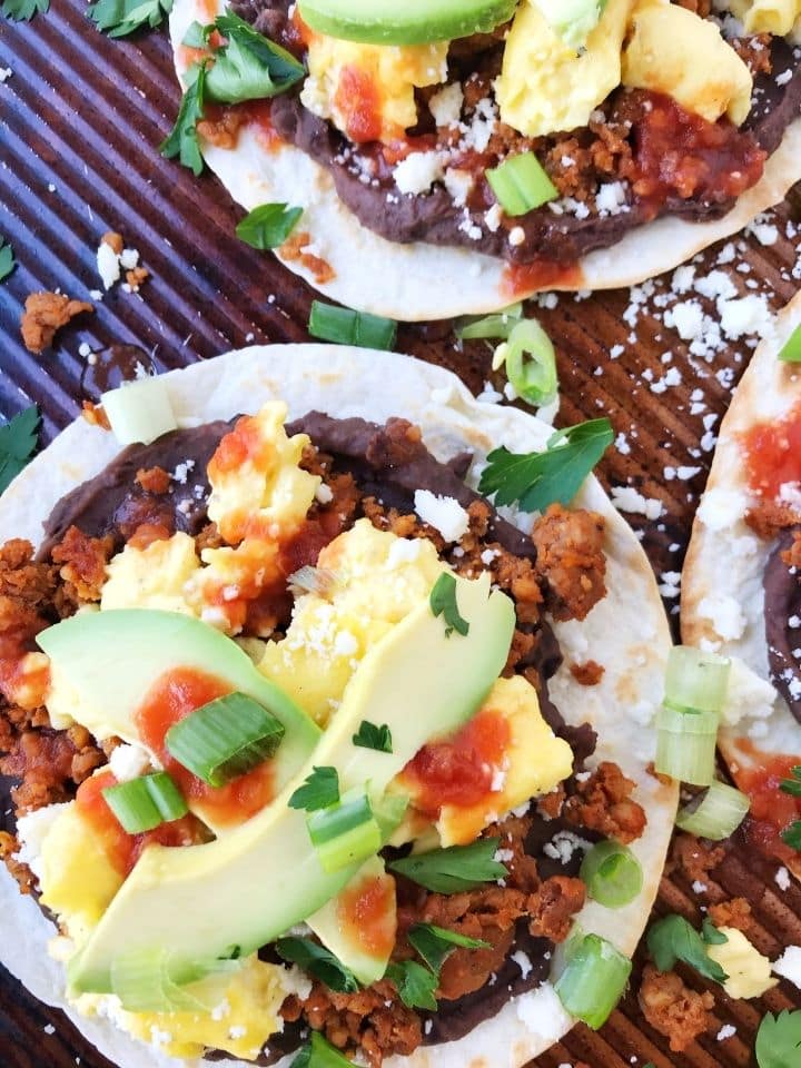 tortillas loaded with refried beans, eggs, avocado, and garnishes