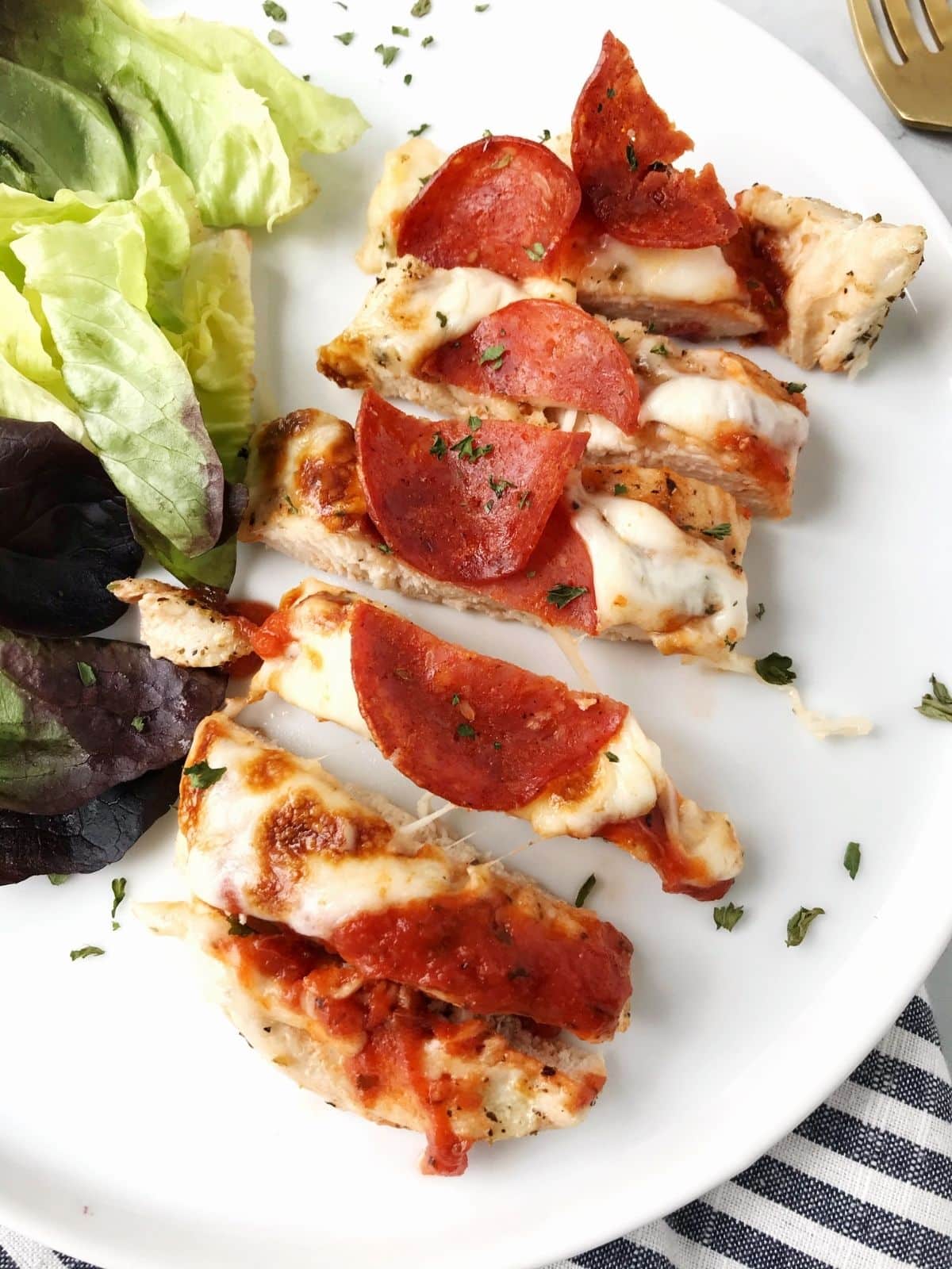 sliced chicken on a plate with a green salad