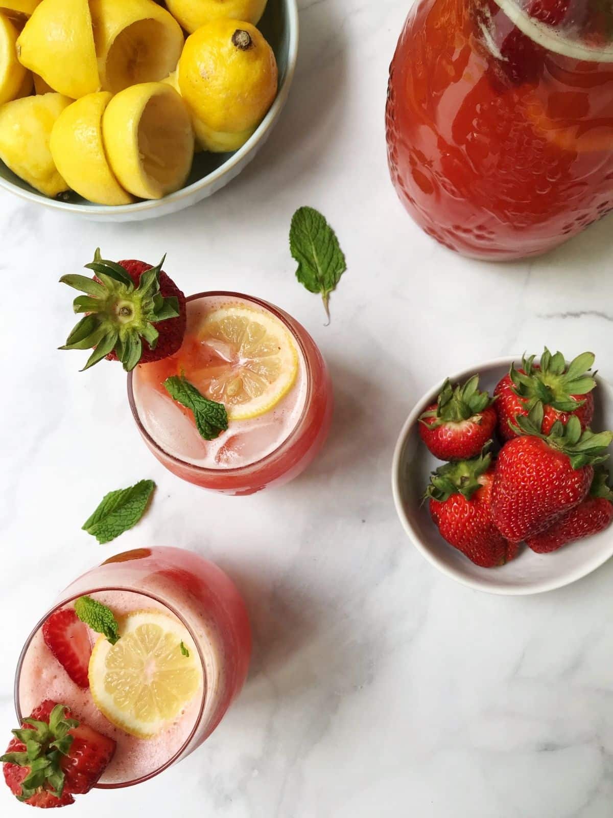 pitcher of lemonade, glasses, and lemons and strawberries