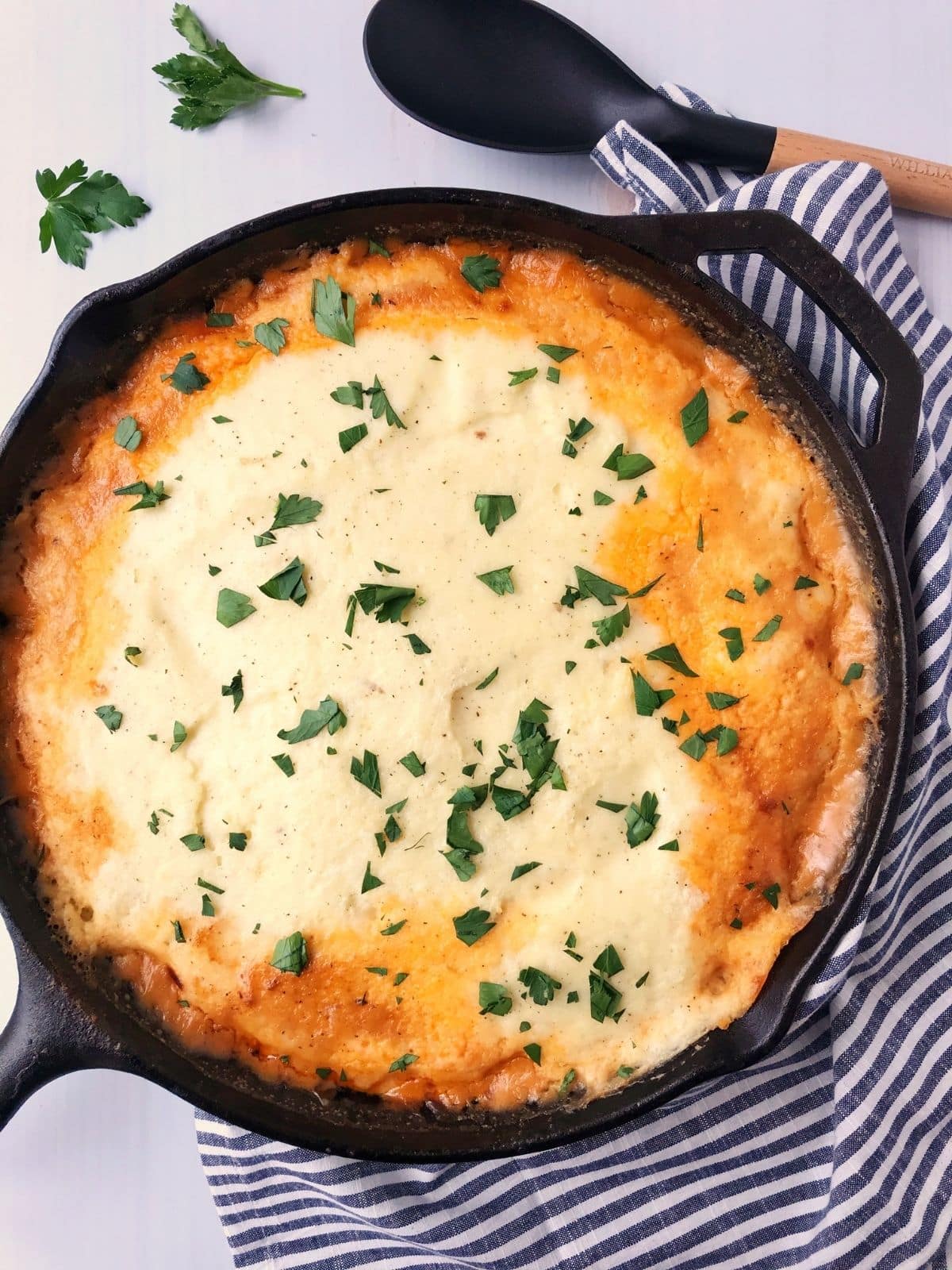 cast iron skillet of shepherds pie garnished with parsley