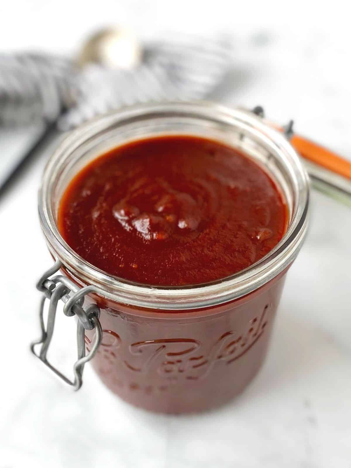 jar of barbecue sauce with spoon in the background