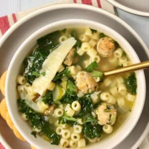 spoon in a bowl of soup with crackers on the side