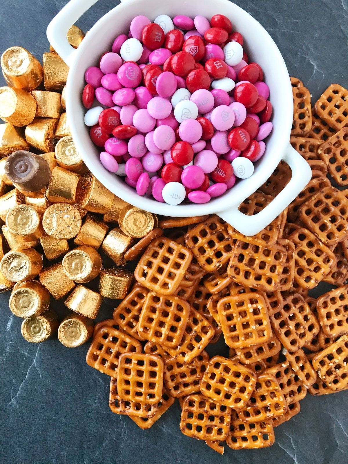 grouping of ingredients - M&M's, rolos, and square pretzels