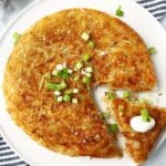 Skillet hash brown on a platter with a slice cut.