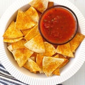 white dish of chips with a bowl of salsa