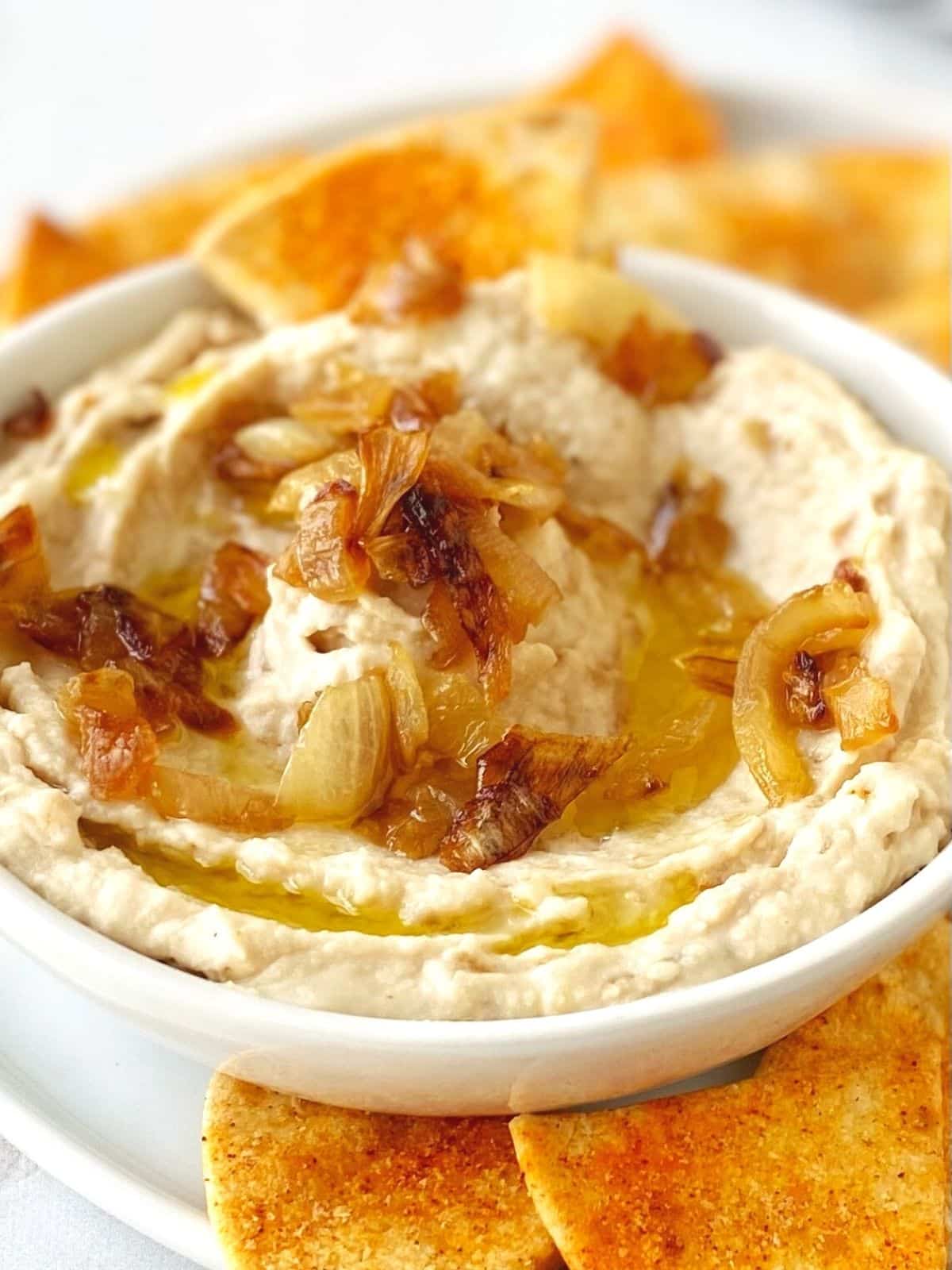 dish of hummus drizzled with olive oil and garnished with caramelized onions