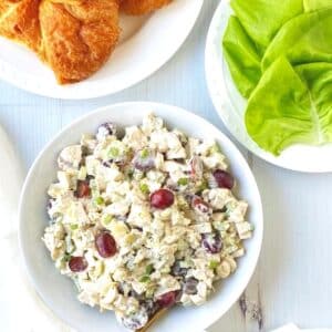 white bowl of chicken salad with croissants and lettuce ready to build sandwiches