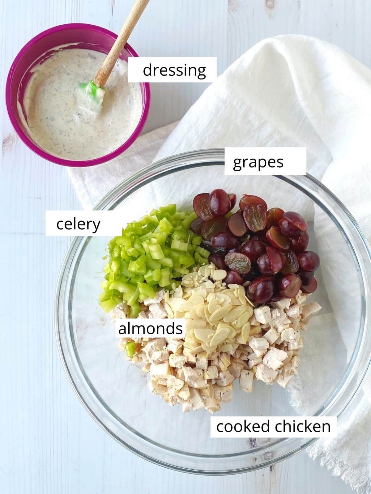 bowl of ingredients - chicken, grapes, celery, almonds, and a small bowl of dressing