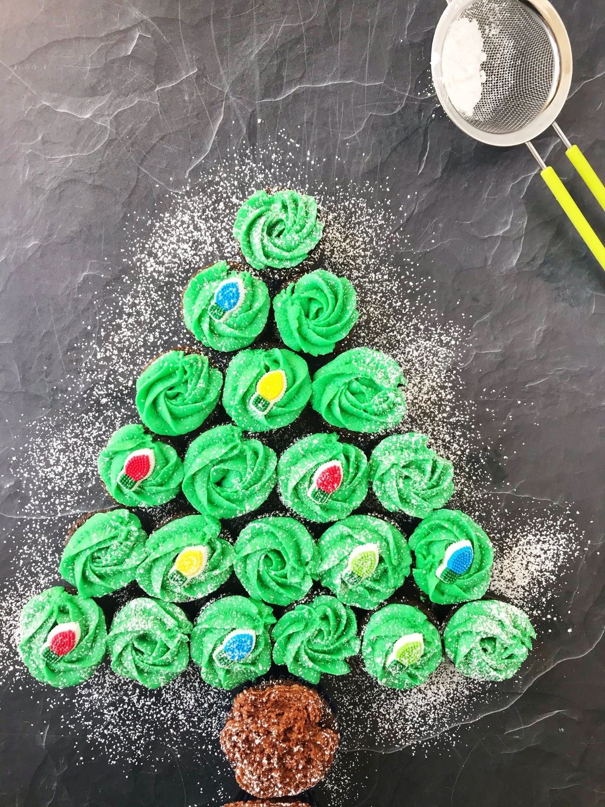 cupcakes arranged in the shape of a tree with powdered sugar dusted over the top