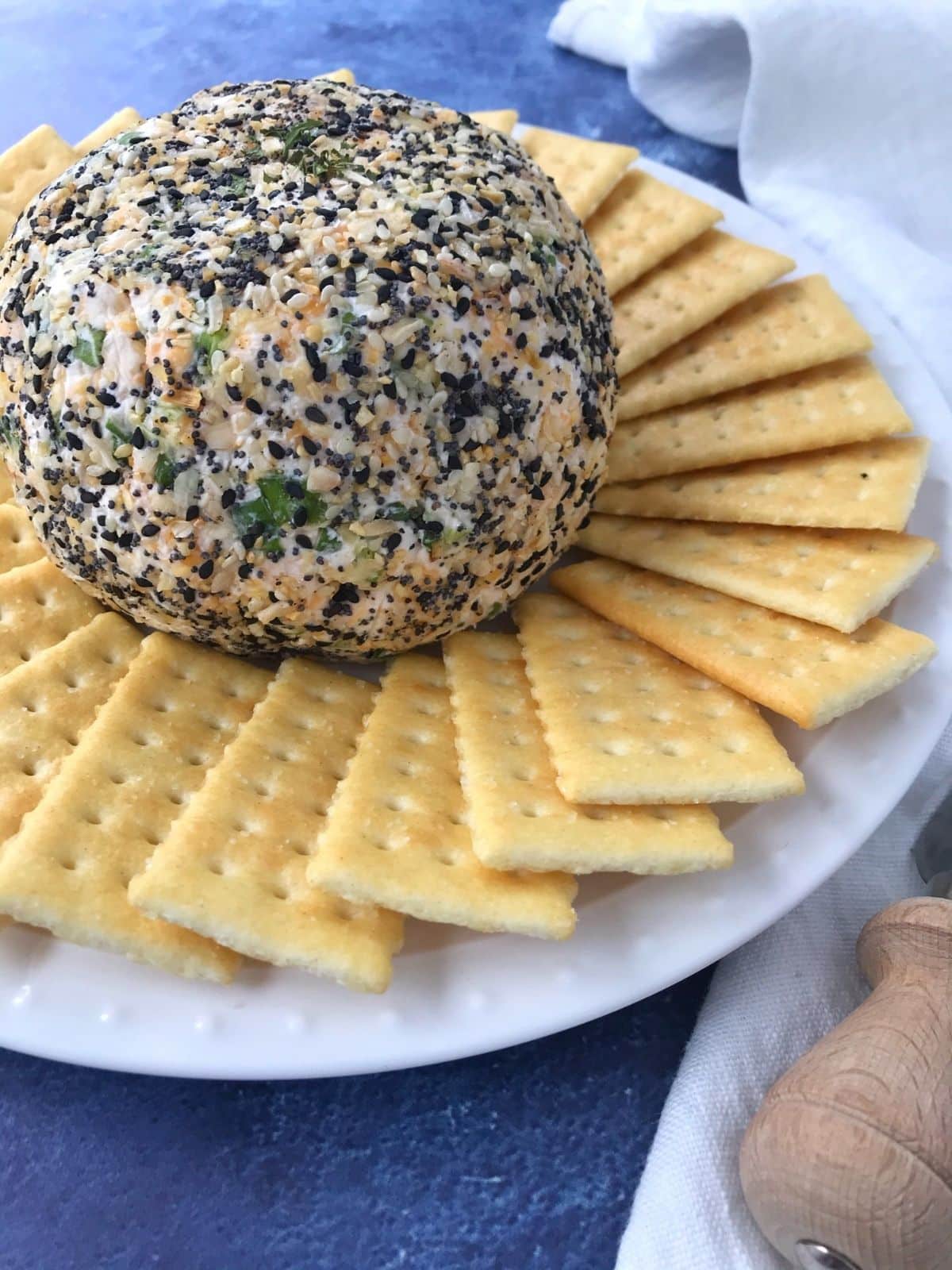 cheese ball on a white plate surrounded by crackers