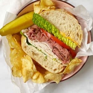 overhead shot of a wedge of sandwich served with chips and a pickle