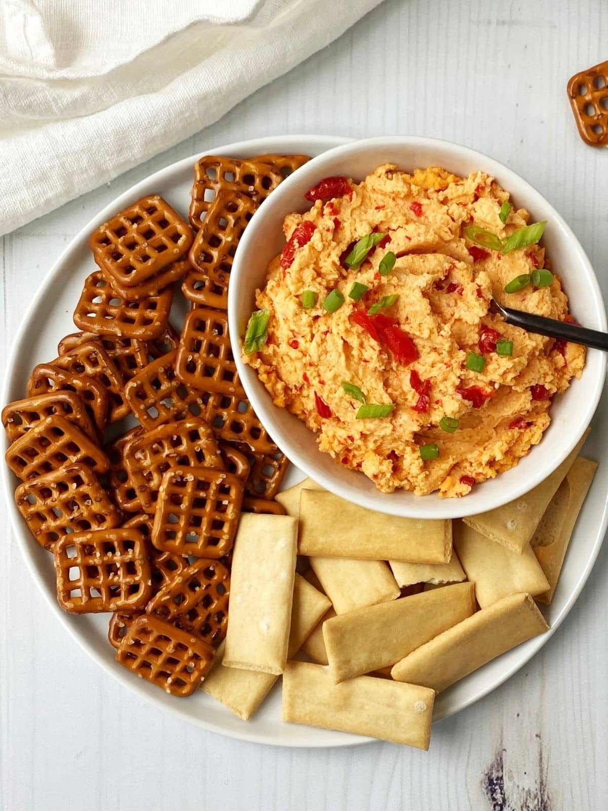 bowl of cheese spread on a plate with pretzels and crackers